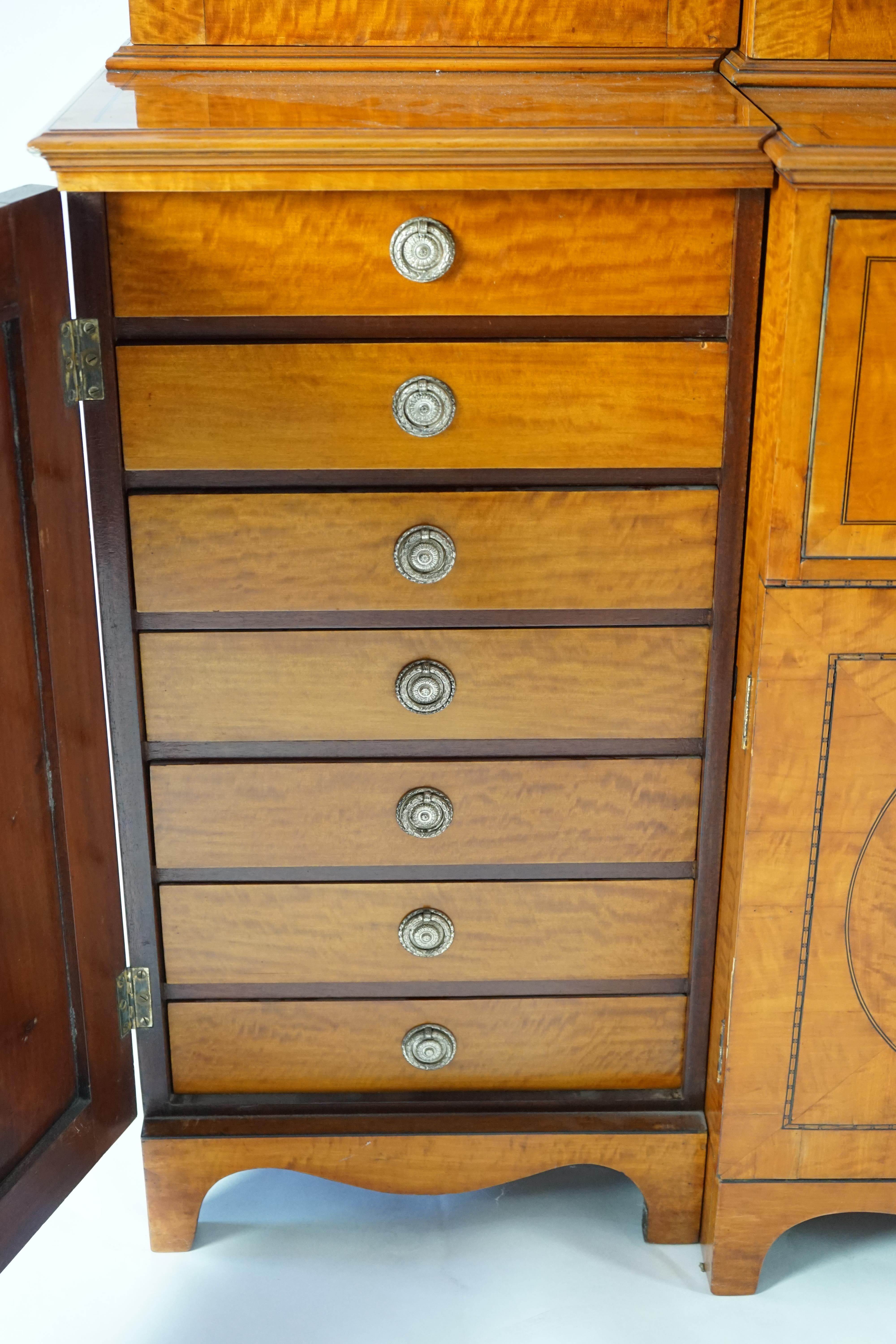 A Sheraton revival ebony strung satinwood breakfront secretaire bookcase